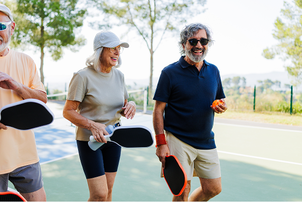 senior couple entering a pickleball court with ball and paddles